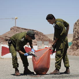 Israeli soldiers collect blood-stained clothes from the scene where a bus was ambushed 