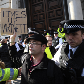 A protester holding a placard referring to Her Majesty's Revenue and Customs (HMRC) boss Dave Hartnett, takes part in a demonstration against corporate tax avoidance in London (Getty)