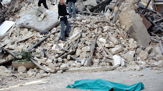 A body lies outside a destroyed building after the L'Aquila earthquake in 2009 (Getty)