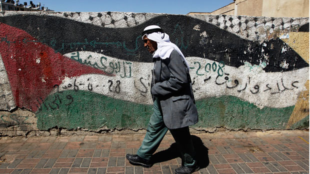 A Palestinian man walks past flag mural (Reuters)