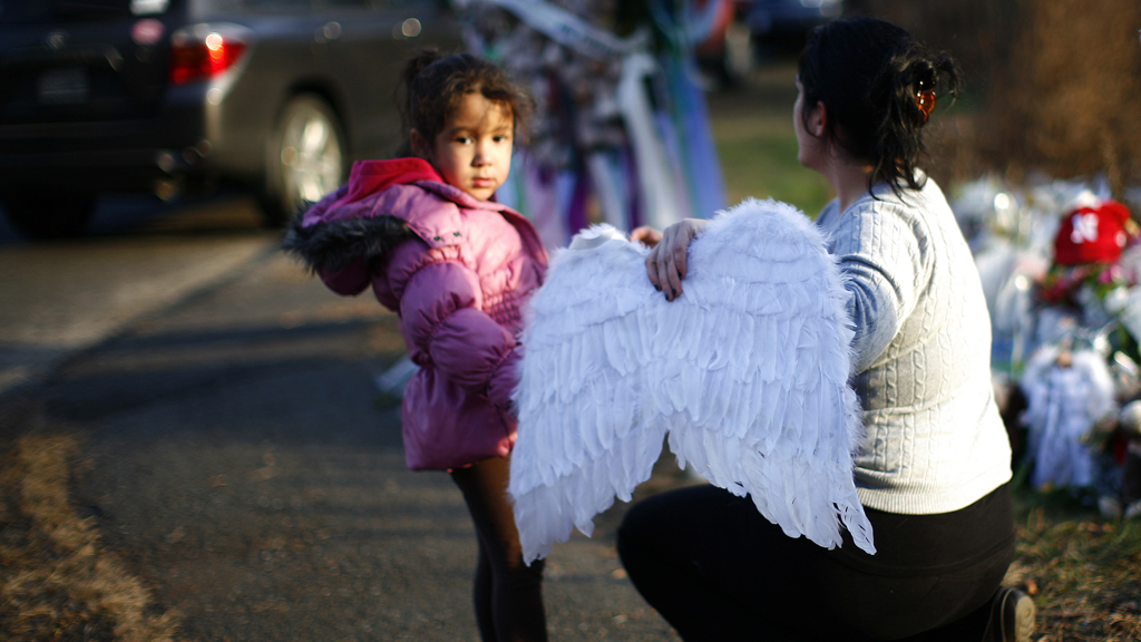 A girl and a woman place angel wings at the Sandy Hook Elementary School sign in Newtown (R)