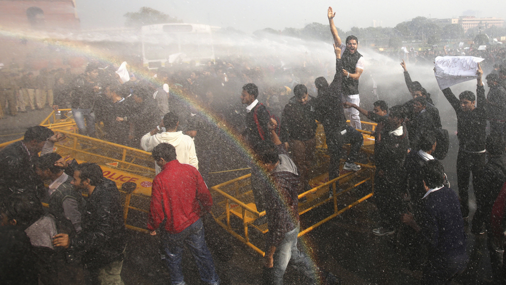 Protestors break through a barricade as police fire water cannons (Reuters)