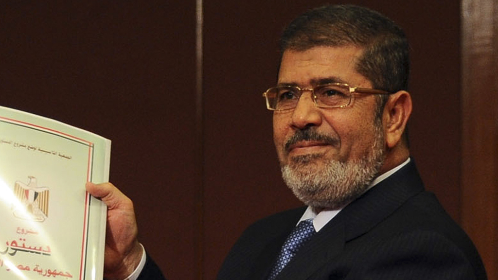 Mohamed Mursi holding the draft constitution (Reuters)