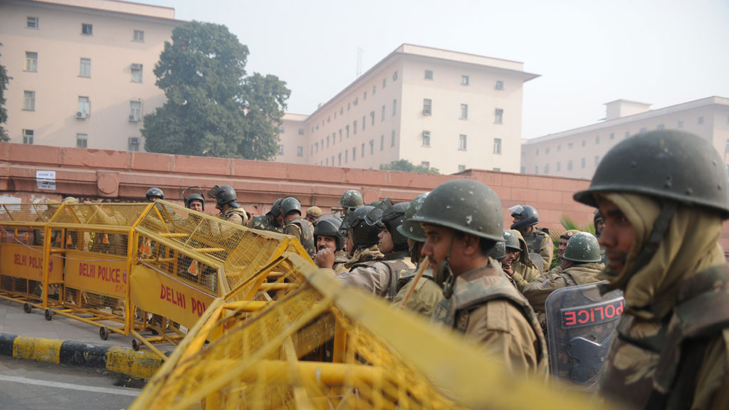 Indian riot police look on as they keep watch along a sealed-off road in Delhi (pic: Getty)