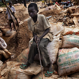 A young boy sits on a stack of ore sacks in the mining village of Bagega (Human Rights Watch)