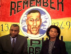 The Parents of murdered black teenager Stephen Lawrence, Neville (L) and Doreen, are seen in this file picture taken February 24, 1999 as they speak to the media in front of a banner of their son. 