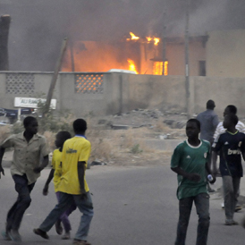 Smoke rises from the police headquarters as people run for safety in Nigeria's northern city of Kano (Reuters)