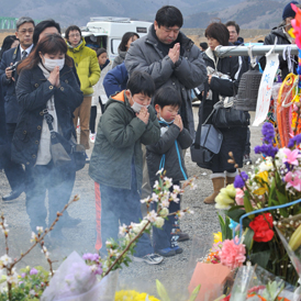 A family pray for 74 elementary school children and 10 teachers who lost their lives in the March 11 earthquake and tsunami, at a memorial in front of the Okawa elementary school (Getty)