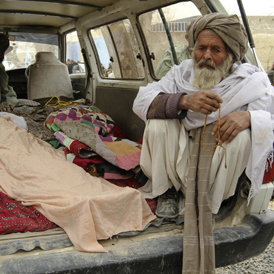 An elderly Afghan man sits next to the covered bodies of people who were killed by coalition forces in Kandahar province (Reuters)