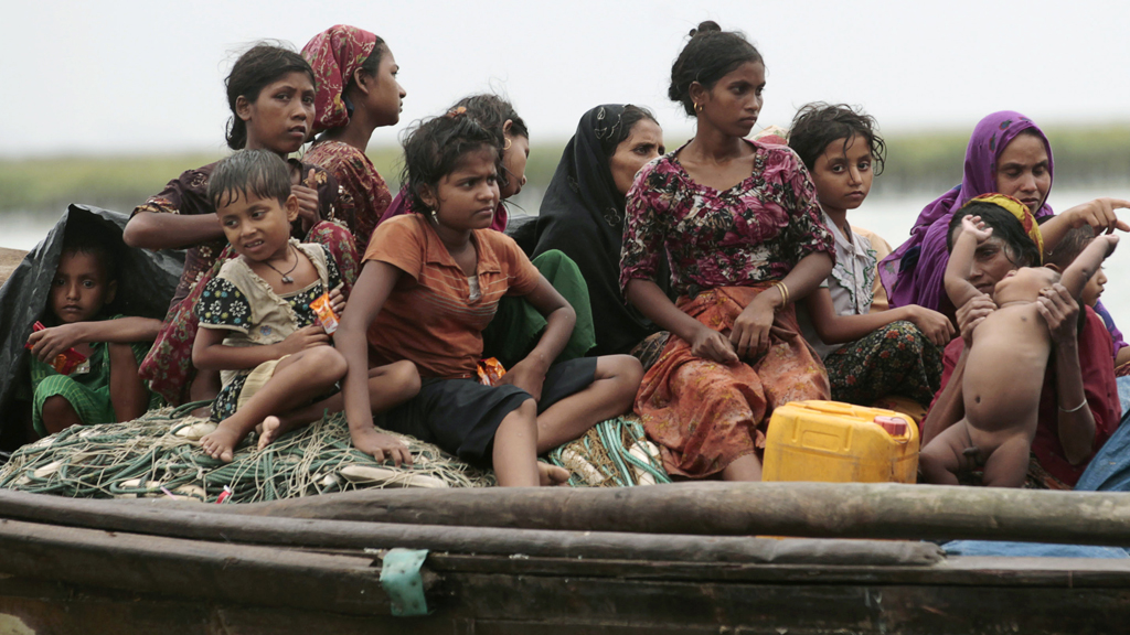 Rohingya refugees from Myanmar sit on a boat as they try to get into Bangladesh in Teknaf in June (Reuters)