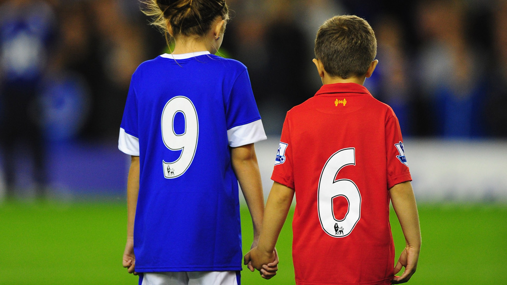 A boy and girl in Liverpool and Everton strips with the numbers 9 and 6 on the back (Getty)
