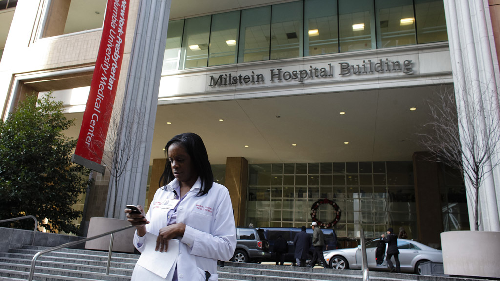A member of the hospital staff walks in front of the Milstein Hospital Building at the NewYork-Presbyterian Hospital