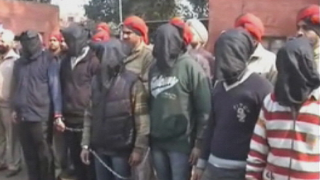 The suspects were shown hooded alongside Indian police