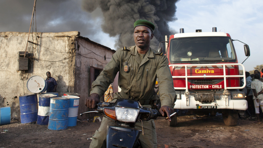 A police officer rides a motorcycle after calling for help near fumes from a fire at Ngolonina market in the Malian capital of Bamako (Reuters)