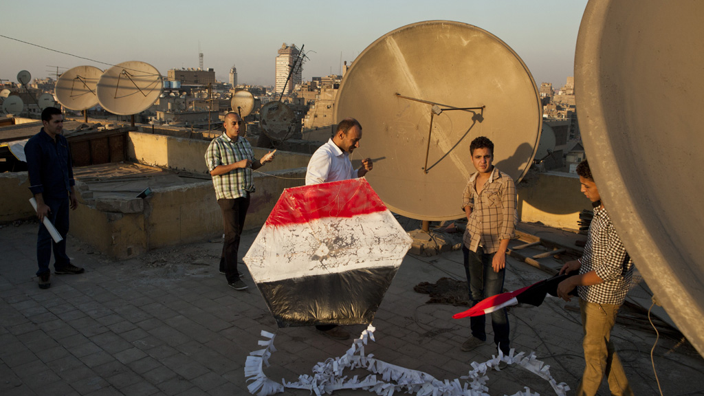 Supporters of the Egyptian Army prepare to fly a kite painted in the colours of the Egyptian flag from a rooftop during a demonstration at Tahrir Square. (Reuters)
