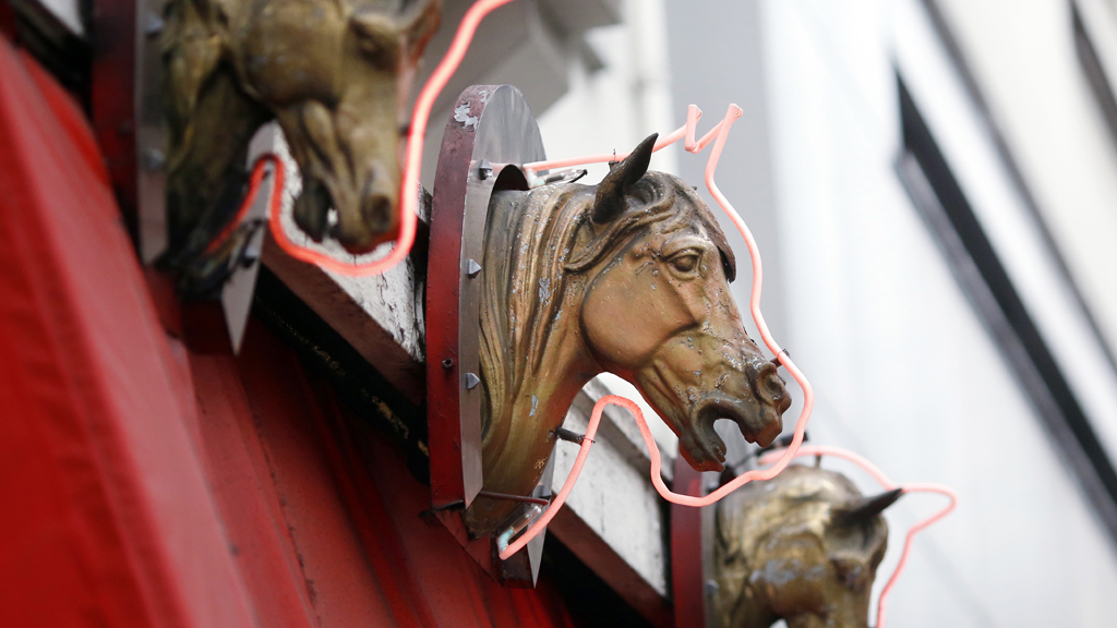 Plastic horses heads decorate the frontage of a French butcher shop (G)