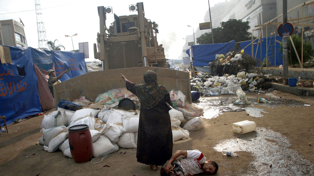 In Egypt a woman stands between a bulldozer and an injured protester the army cracked down on pro-Morsi demonstrators in August (G/R)