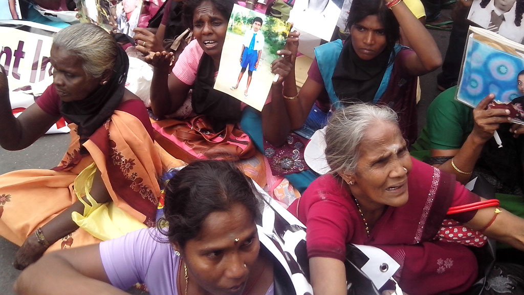 Tamil women cry as they hold up images of their disappeared family members during the war against Liberation Tigers of Tamil Eelam (LTTE) at a protest in Jaffna, about 250 miles north (G/R)