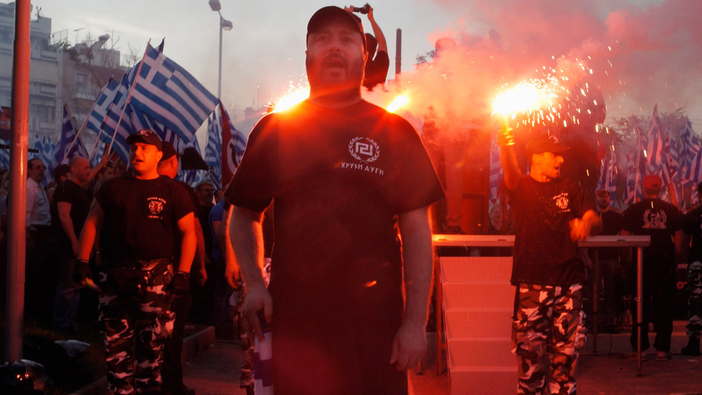 Members of the extreme-right Golden Dawn party stand around a stage and chant the National anthem during a gathering on May 26, 2013 in Athens, Greece. 