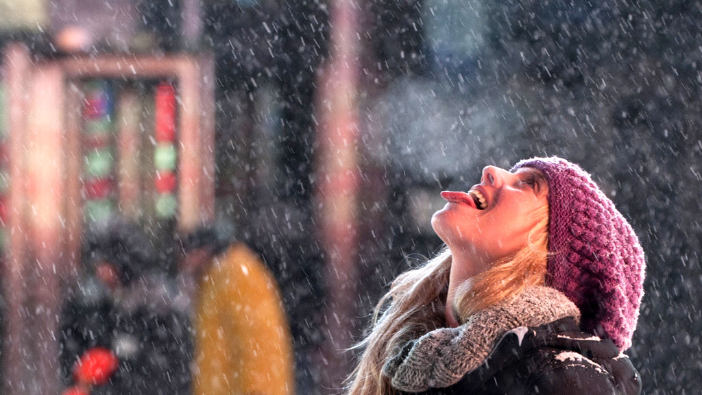 A tourist in Times Square, New York, makes the most of the snowfall (R)