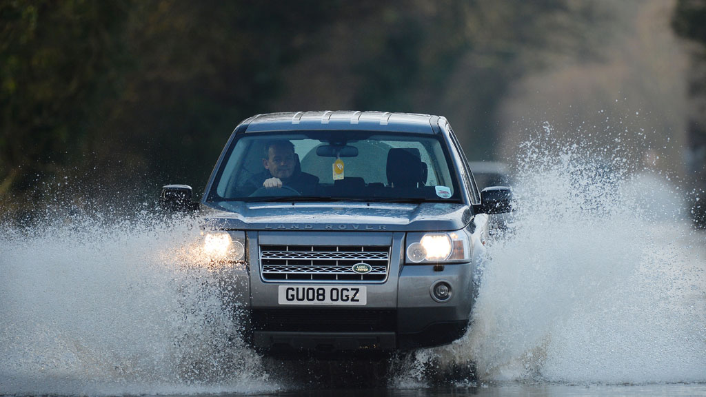A car drives through flood water in Yalding, Kent (R)
