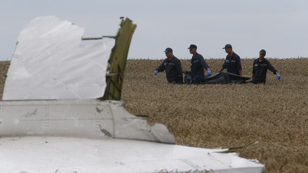 Investigators carry a body from the MH17 crash site