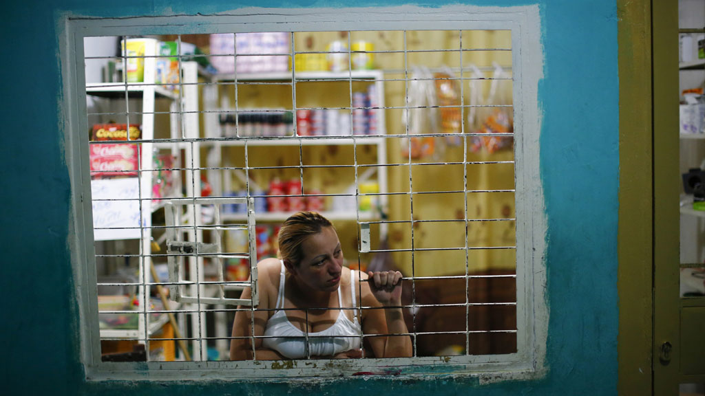 A woman looks out of a window at her shop 