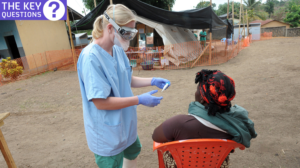A nurse examines a patient the in-take area at a centre for victims of the Ebola virus in GuÃ©ckÃ©dou, Guinea (credit: Getty Images)