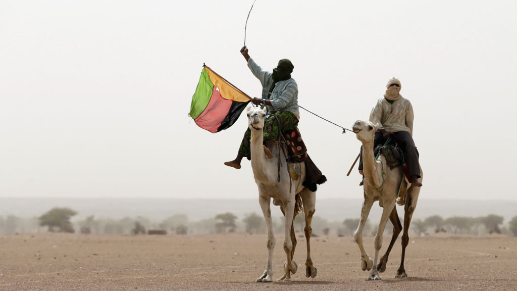 A Tuareg man holds the MLNA flag in July 2013