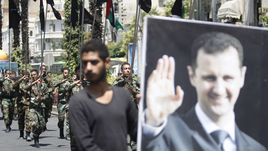 Syrian army soldier holds picture of Assad (Reuters)