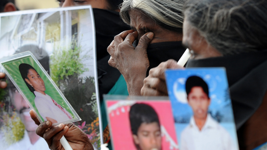 Tamil women in Jaffna hold up pictures of the dead and missing in November 2013.