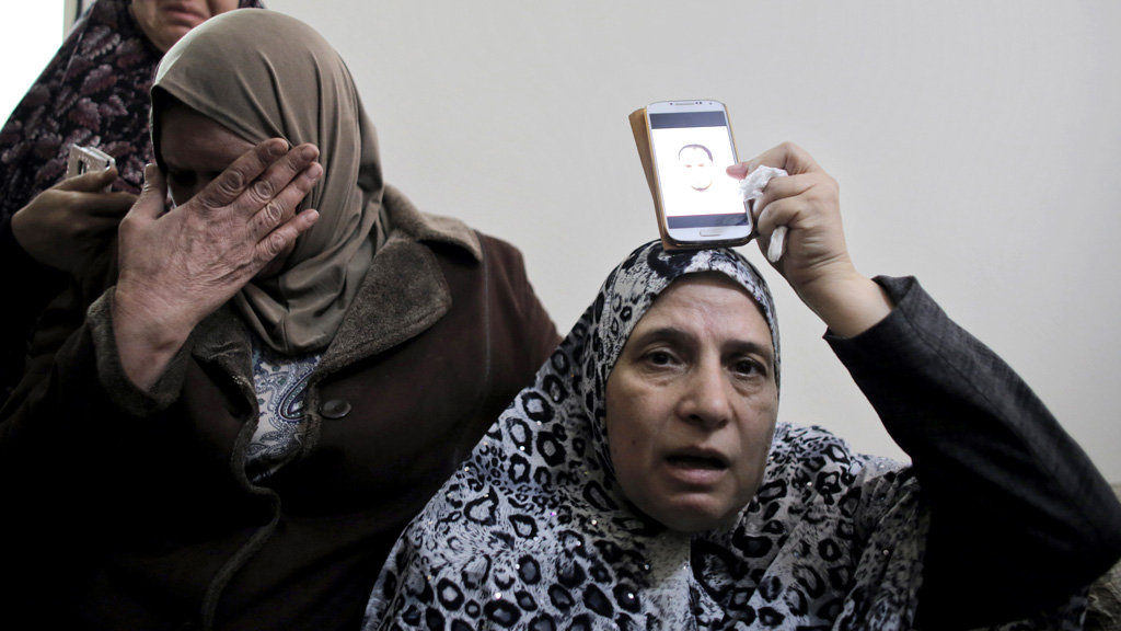 The motehr of Moataz Hejazi holds up a picture of him (Reuters)