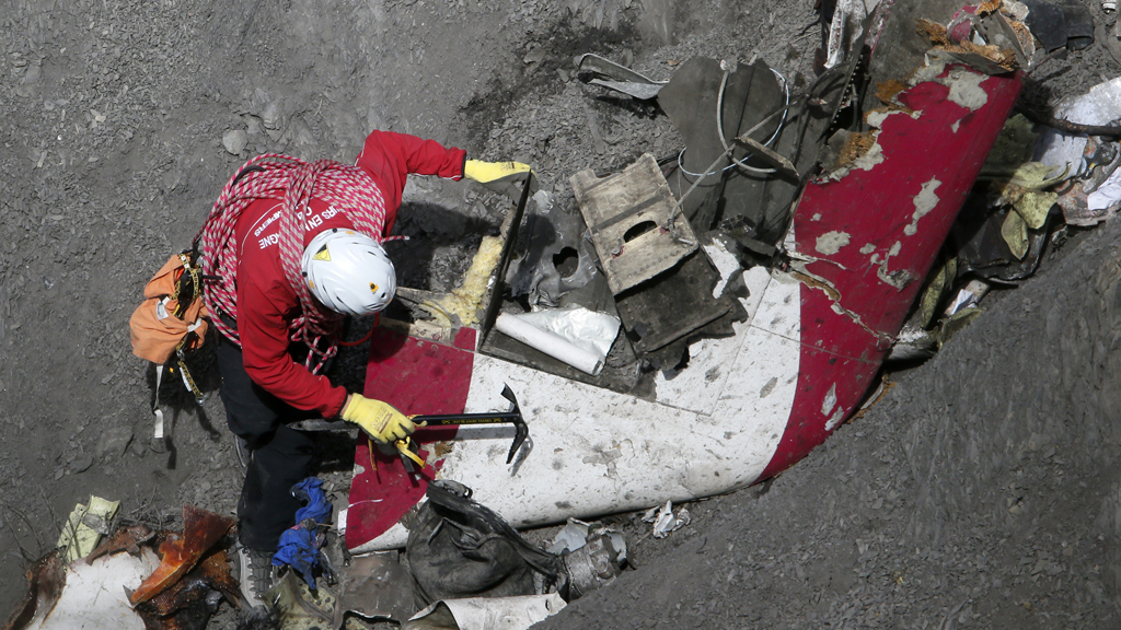 A member of the recovery team searches through crash debris on the mountainside (Reuters)