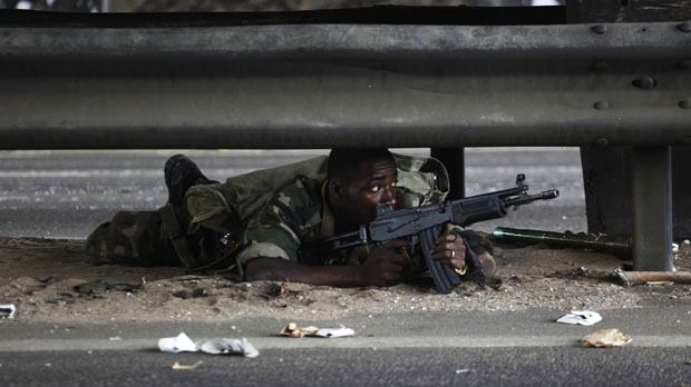 A soldier loyal to Alassane Ouattara takes cover in Abidjan (reuters)