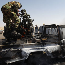 Libya: Rebel fighters attempt to salvage weapons from burning Gaddafi vehicle. (Reuters)
