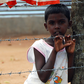 A young Tamil boy stands behind a barbed-wire fence in the Menikfam Vanni refugee camp located near the town of Chettekulam in northern Sri Lanka (Reuters)