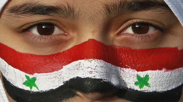 Protester with face painted in Syria flag colors shouts slogans outside Syrian embassy in Amman (Reuters)