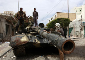 Rebel fighters stand on top of a captured tank belonging to forces loyal to Muammar Gaddafi