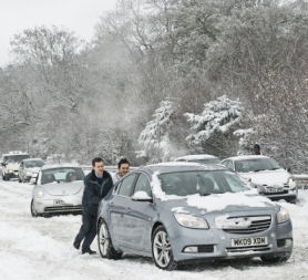 Motorists push a car in the snow on the A3 near Guildford in southern England. Reuters