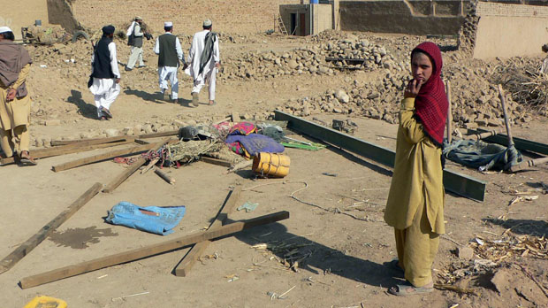 Pakistani tribesepeople stand among the debris of houses after a suspected US drone attack. (Reuters)