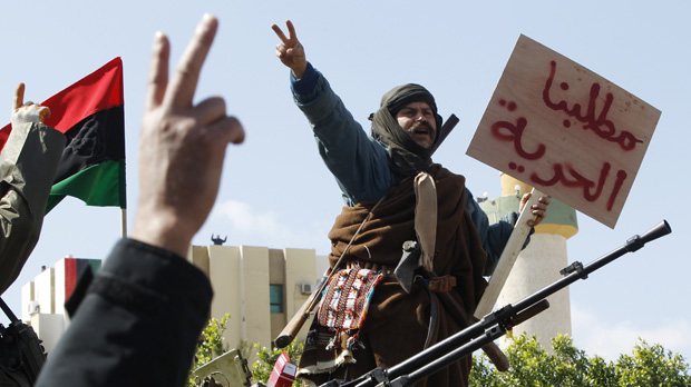 Libya protests: a man stands on a tank holding sign that reads 