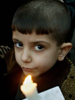 Iraq inquiry: An Iraqi boy holds a candle during a rally on the last night of 2002 in front of the UN office in Baghdad Dec 31, 2002. (Reuters)
