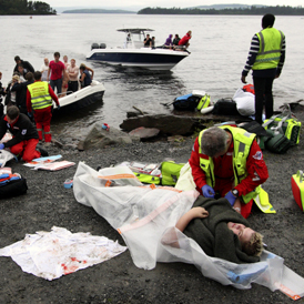 A wounded woman is brought ashore opposite Utoya island in Norway after being rescued from a gunman who went on a killing rampage (Getty)