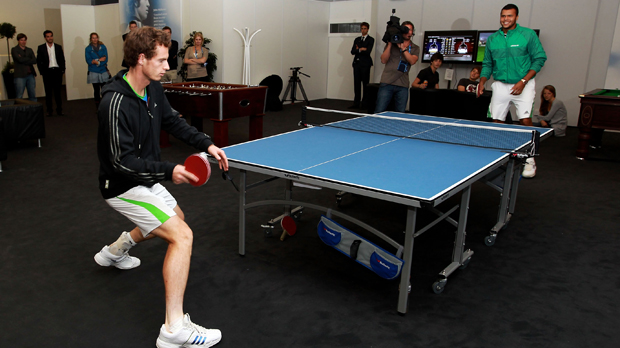Andy Murray of Great Britain (L) and Jo-Wilfred Tsonga of France play table tennis in the players lounge due to the postponement of the final of the ATP tournament at Queen's tennis club