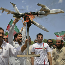 Activists hold up a burning mock drone aircraft during a rally in Peshawar. (Reuters)