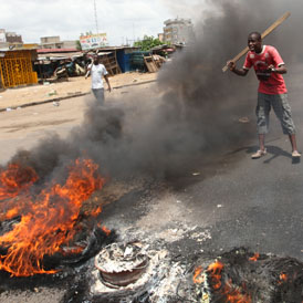 Anti-Gbagbo protesters near a roadblock and burning tyres in the Abobo area of Abidjan (reuters)