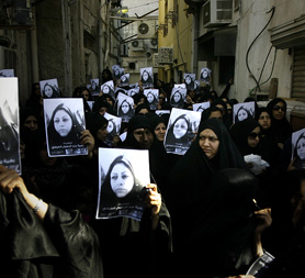 Bahraini women hold placards with the image of the dead woman Bahiya al-Aradi
