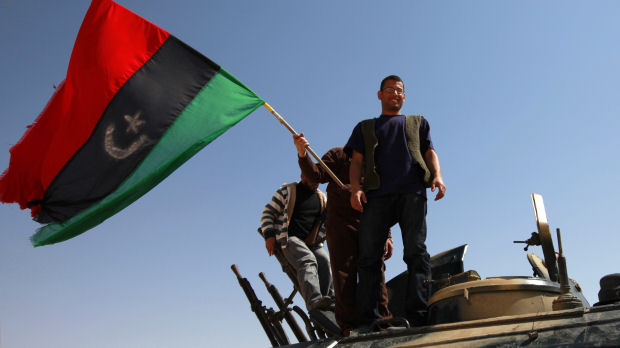Rebel fighters celebrate by waving a Kingdom of Libya flag on the outskirts of the town of Ajdabiya (Reuters)
