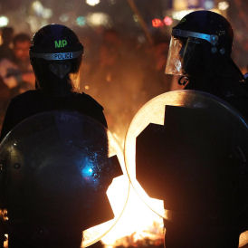 Riot police stand in front of a burning barricade during clashes with protesters after a march in protest against government spending cuts (Getty)