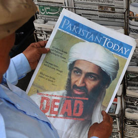 A man reads a newspaper article about Osama bin Laden's death.